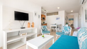 A modern living room with a flat-screen TV, white furniture, a dining area, and a kitchen in the background. - "Erizo De Mar" with Sea Views, Wi-Fi, and Air Conditioning (Tourist Tax Included) (Felanitx)