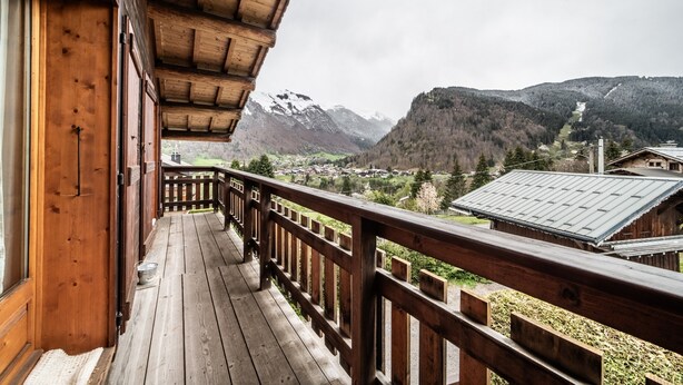 Un balcón de madera con vistas a un paisaje montañoso.