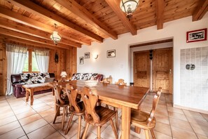 A wooden dining area with a large table and chairs, a sofa, and a chandelier.