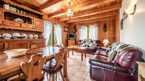Un interior de madera con una mesa de comedor, sillas, un sofá y un televisor.