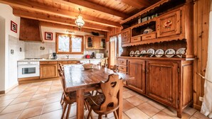 Una cocina de madera con una mesa de comedor y sillas, horno empotrado y salpicadero de azulejos.
