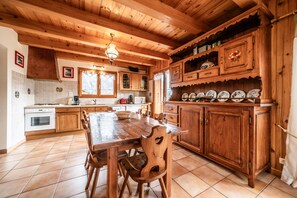 A wooden kitchen with a dining table and chairs, a built-in oven, and a tiled backsplash.