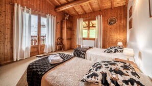 Una habitación de cabaña de madera con dos camas, una ventana, una puerta y una pequeña mesa.