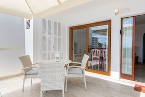A balcony with wicker furniture, a glass door, and a view of buildings.