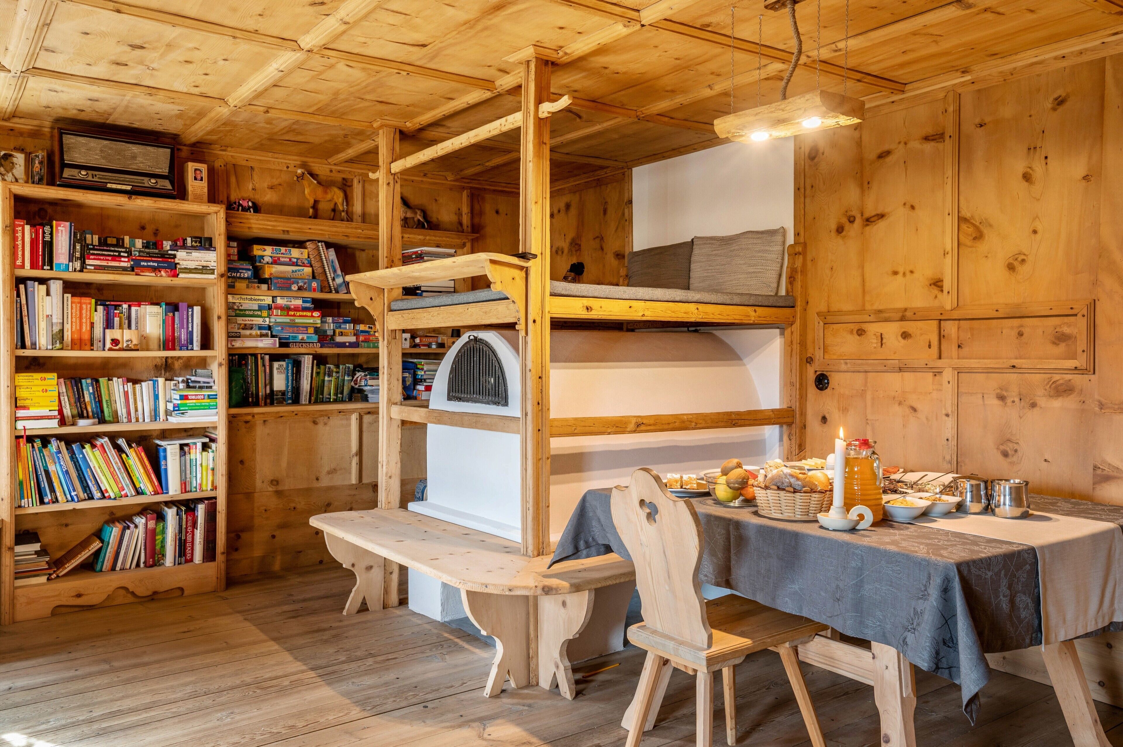 Ein Holzhütten-Interieur mit Etagenbett, Bücherregalen, einem Esstisch mit Kerze und rustikalem Charme.