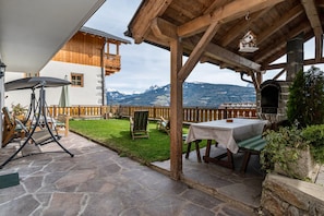 A patio with stone flooring, wooden furniture, and a view of mountains. - Apartment 'Malsötscherhof A' with Mountain View, Private Terrace and Wi-Fi (Villanders)