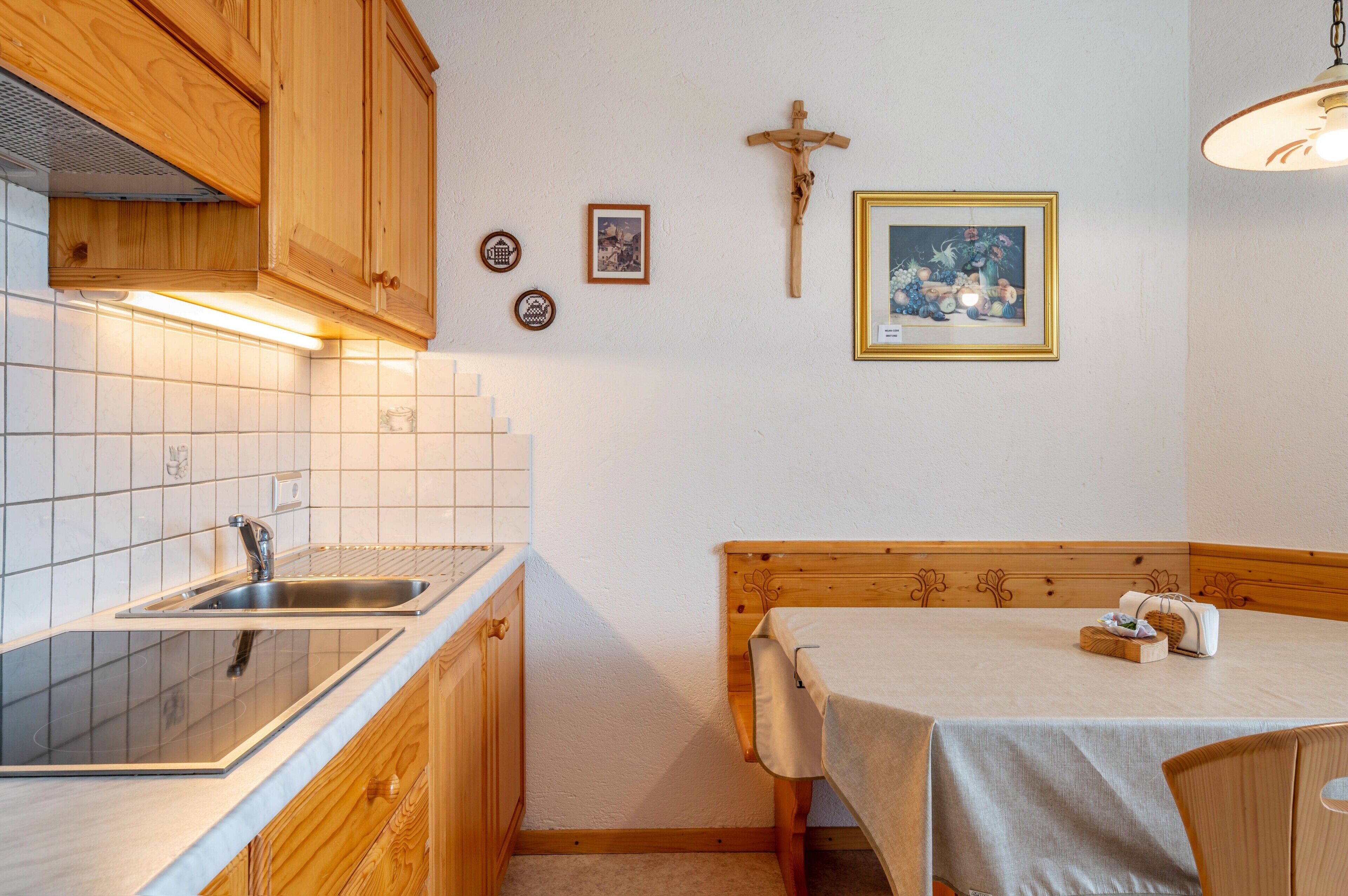 Une cuisine avec des meubles de rangement en bois, un évier et un coin repas comprenant une table et des chaises.