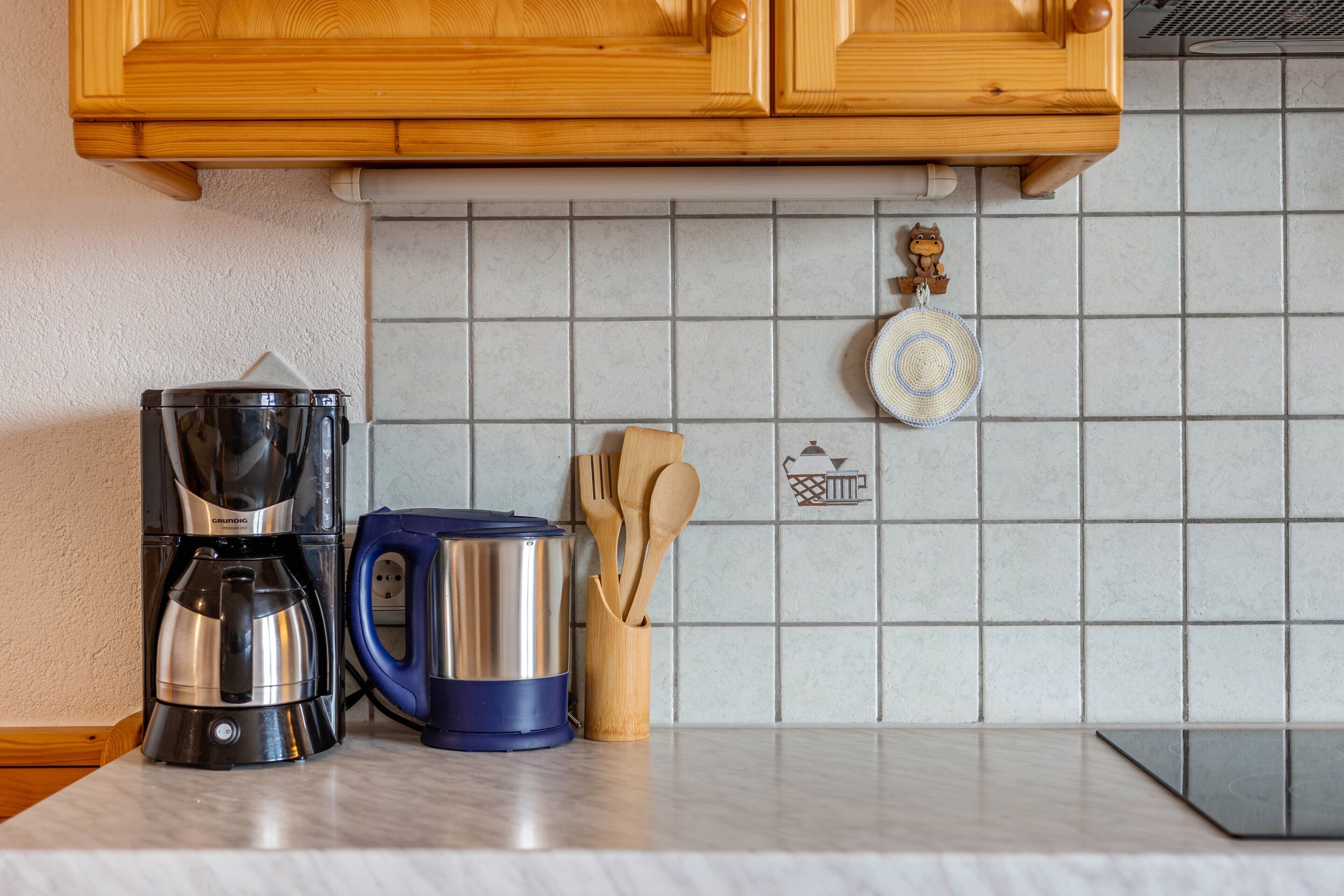 Eine Küche mit Kaffeemaschine, Wasserkocher und Holzkochlöffeln auf der Arbeitsfläche.
