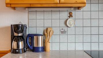Eine Küche mit Kaffeemaschine, Wasserkocher und Holzkochlöffeln auf der Arbeitsfläche.