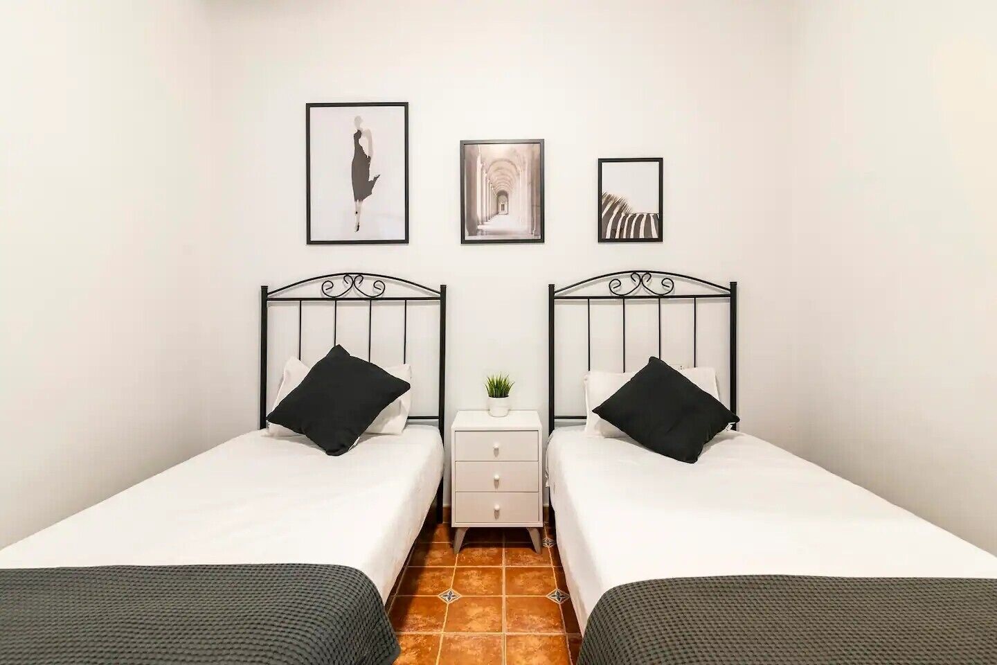 Een kamer met twee bedden, een nachtkastje en drie ingelijste foto’s aan de muur.