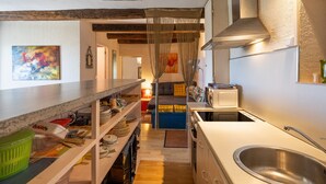 Een kleine keuken met een lange werkblad, een inbouwoven en een roestvrijstalen spoelbak.