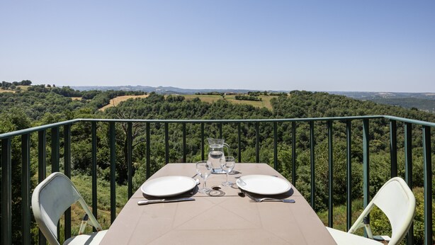 Een tafel gedekt voor twee met een prachtig uitzicht op een bebost landschap.