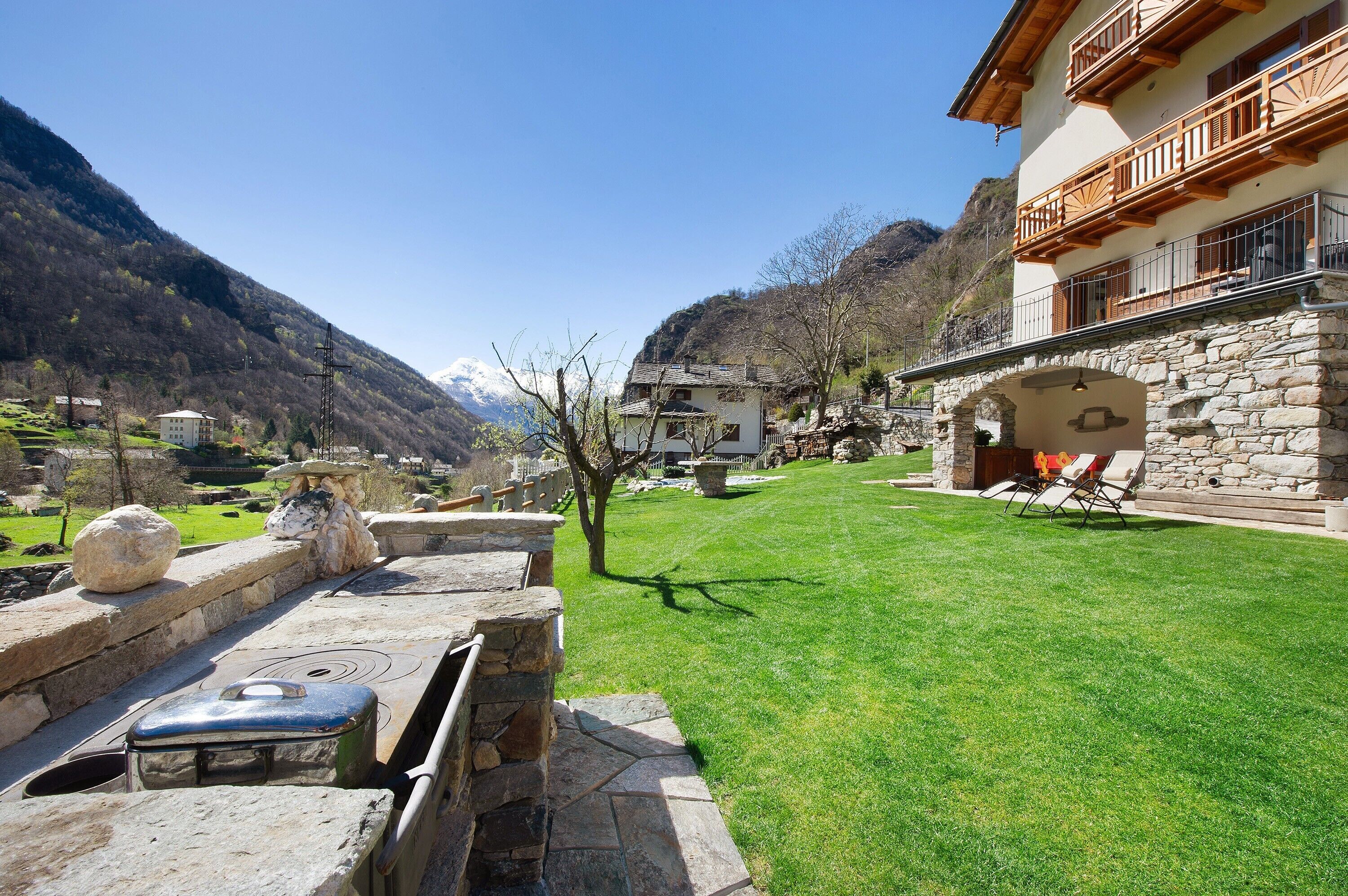 A stone building with a balcony, a stone fireplace, and a well-maintained lawn.