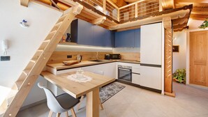 Une cuisine moderne avec un escalier en bois, une table à manger et un four encastré.