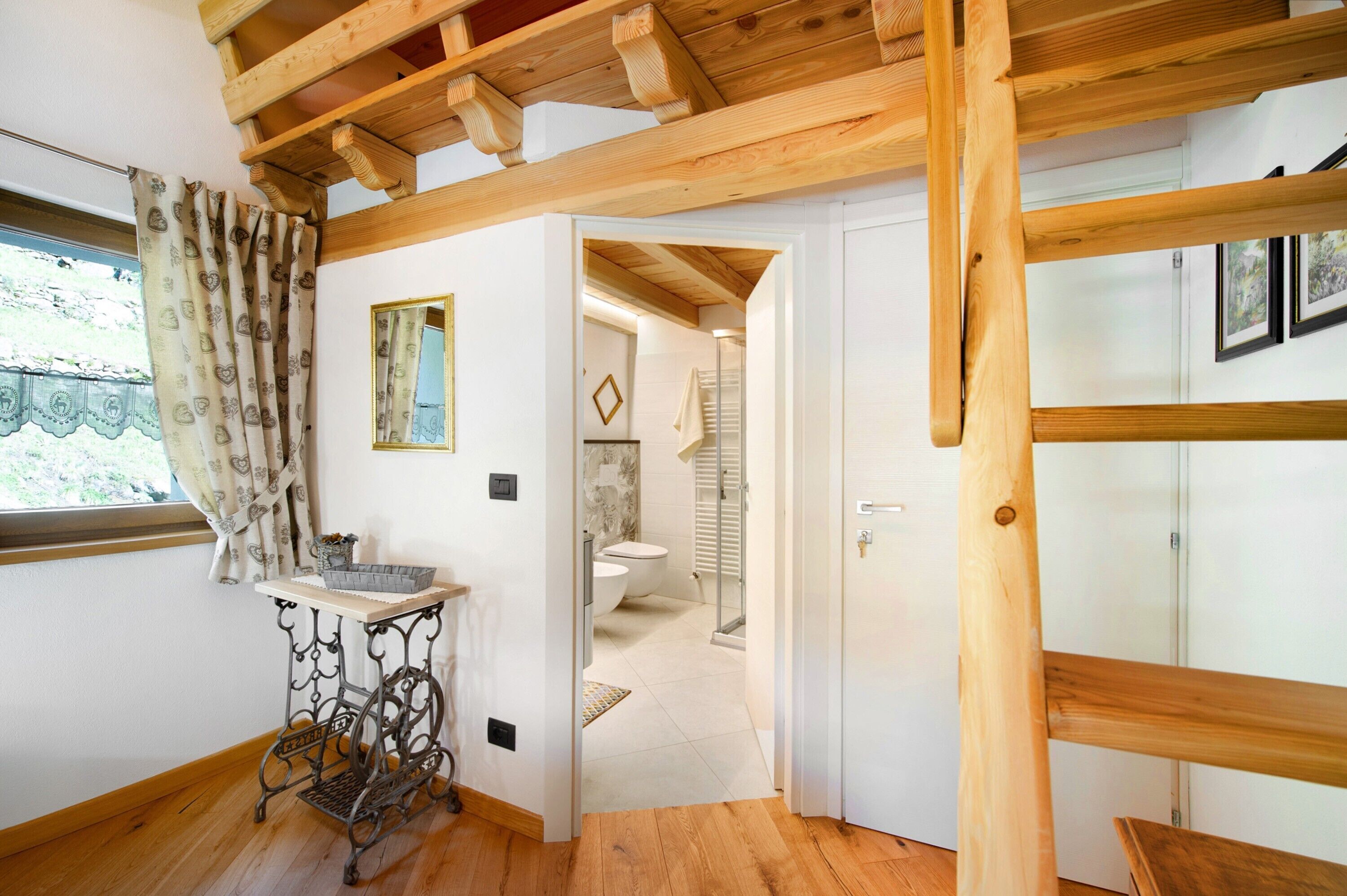 A wooden ceiling, a small table with a basket, a mirror, and a door leading to a bathroom.