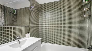 Een badkamer met een witte wastafel, een bad en een douche met een handdouche.
