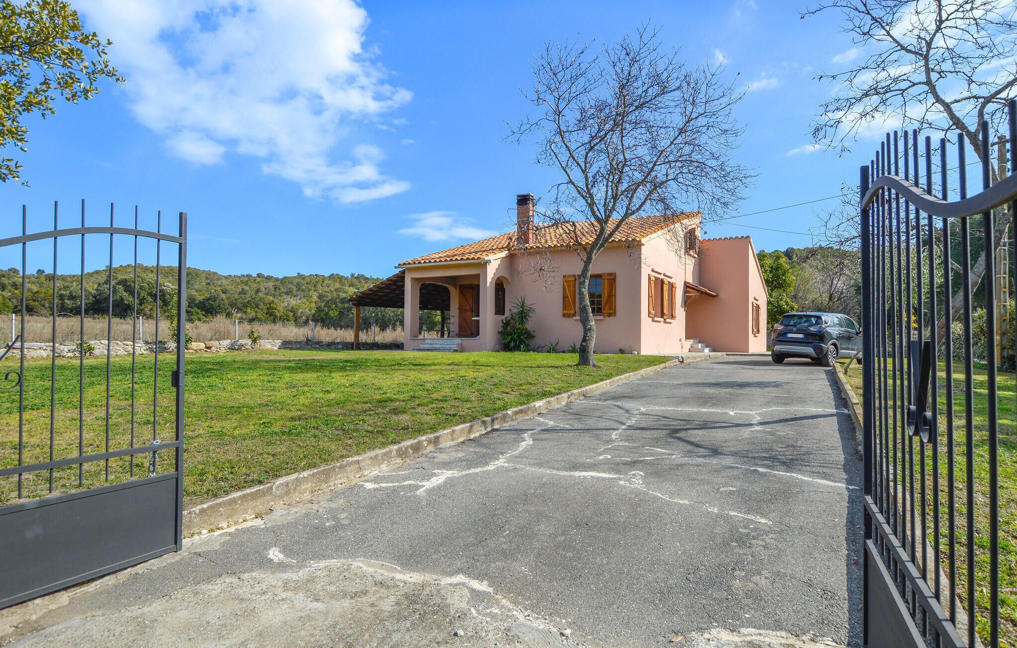 A house with a paved driveway leading to a gated entrance.