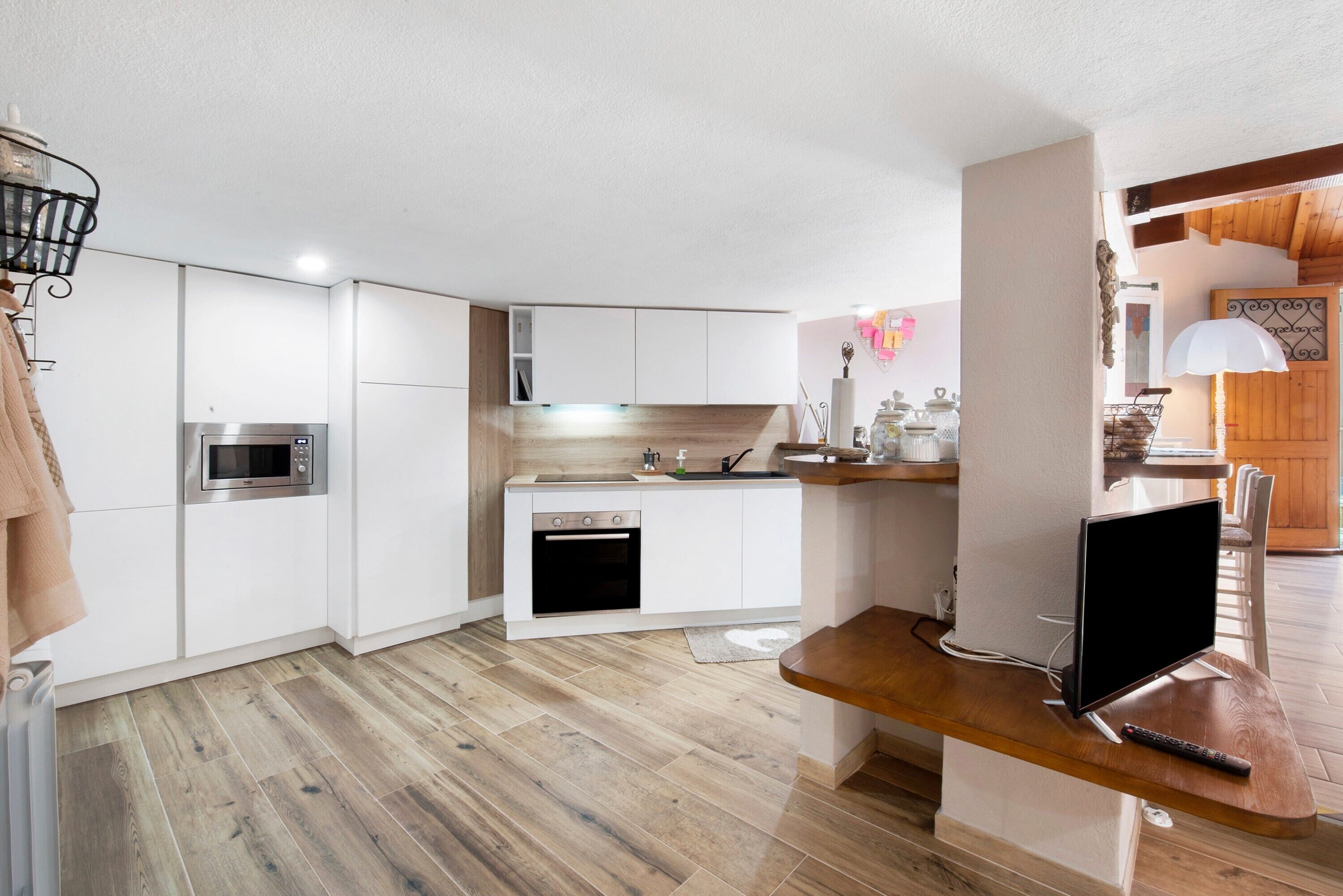 A modern kitchen with white cabinetry, a built-in oven, and a wooden countertop.
