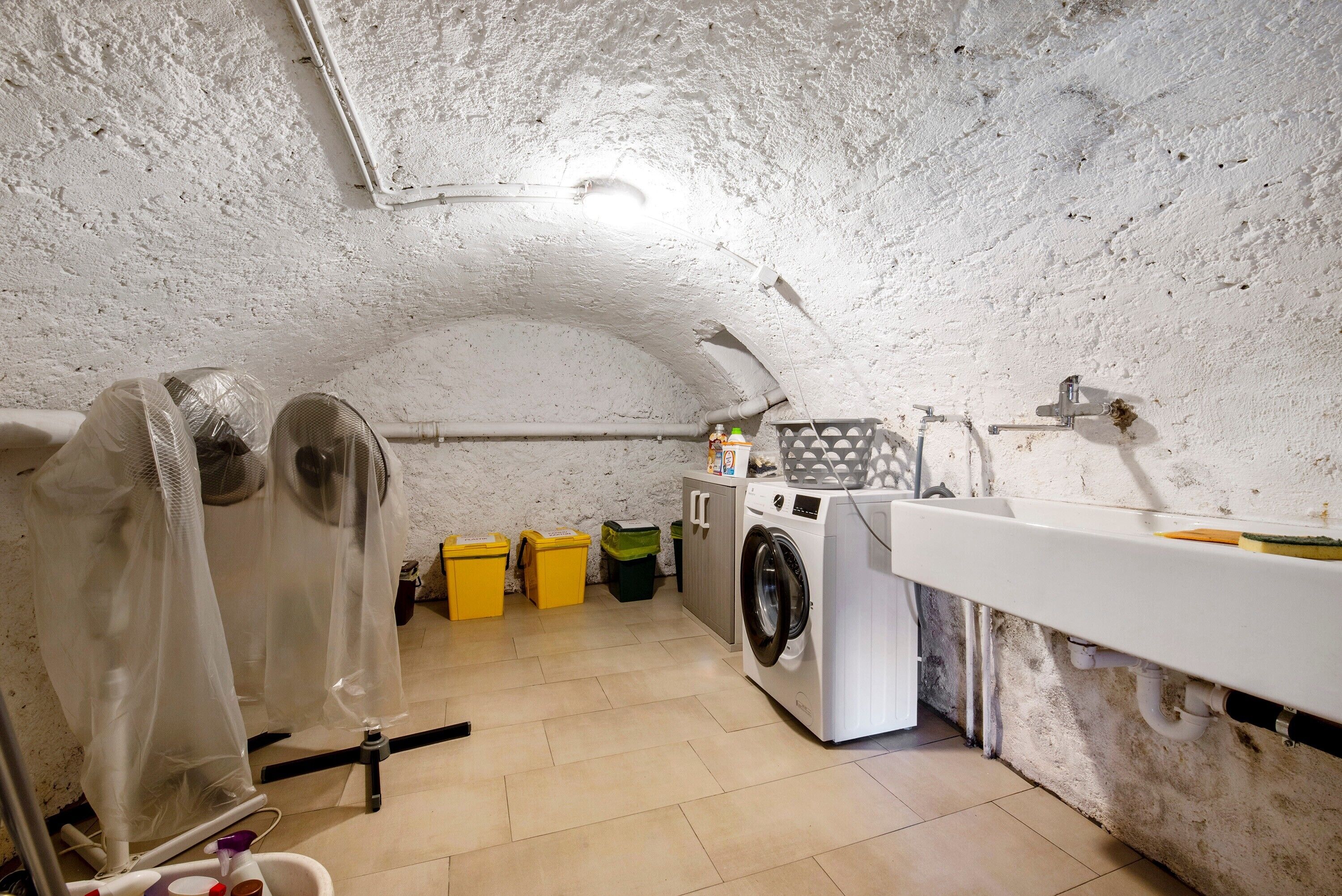 Une buanderie équipée d’un lave-linge, d’un évier et de bacs de rangement.