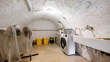 Une buanderie équipée d’un lave-linge, d’un évier et de bacs de rangement.
