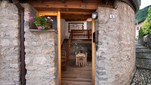 Un bâtiment en pierre avec un escalier en bois menant à une salle à manger équipée d’une table et de chaises.