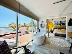 Un dormitorio moderno con un ventanal grande, una bañera y una cama.
