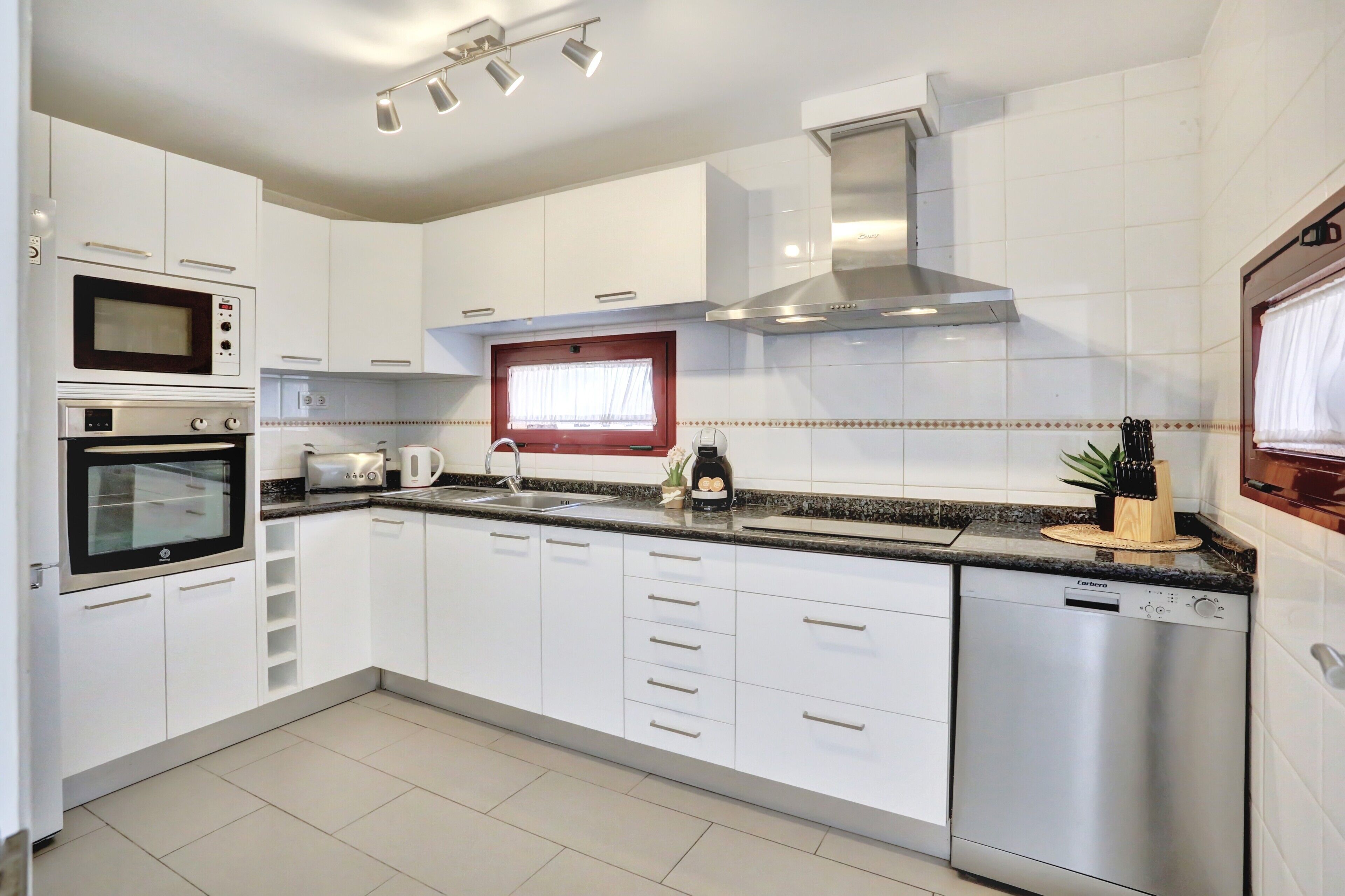 A modern kitchen with white cabinets, a built-in oven, microwave, and dishwasher.