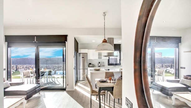 Een modern appartement met een eethoek, keuken en een grote schuifpui naar een balkon.