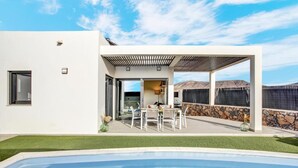 Een modern huis met zwembad, terras en uitzicht op de bergen.