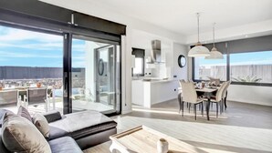 Een modern appartement met een eethoek, keuken en een grote schuifdeur die uitkomt op een balkon.
