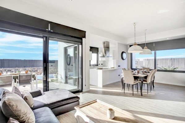 A modern apartment with a dining area, kitchen, and a large sliding glass door leading to a balcony.