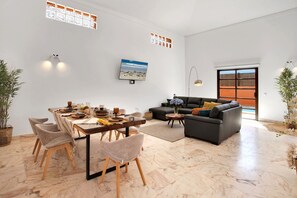A modern living room with a dining area, a sofa, and a TV. - Vacation Home 'Villa Corralejo' with Private Pool, Private Terrace and Wi-Fi (Geafond)
