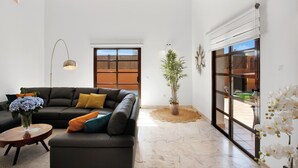 A modern living room with a sectional sofa, a round coffee table, a floor lamp, and a large window with a view.