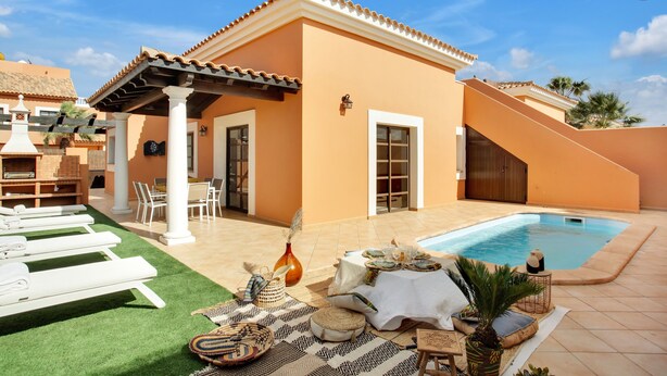A poolside area with lounge chairs, a table with a white tablecloth, and a small pool.