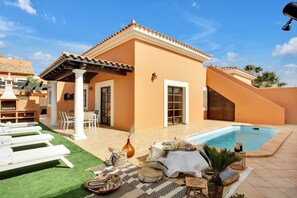 A poolside area with lounge chairs, a table with a white tablecloth, and a small pool. - Vacation Home 'Villa Corralejo' with Private Pool, Private Terrace and Wi-Fi (Geafond)