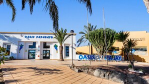 A building with a sign reading 'Oasis Papagayo' and another sign for 'Oasis Papaya.' - Holiday Home 'Apartamento Papagayo' with Shared Pool, Private Terrace & Wi-Fi (Corralejo)