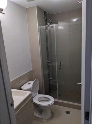 A bathroom with a toilet, a shower enclosure, and a sink. - Cozy Condo near Port-of-Spain (Port of Spain)