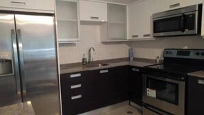 Una cocina moderna con electrodomésticos de acero inoxidable, armarios blancos y encimera de granito.