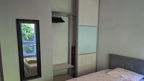Un dormitorio con cama, espejo y armario.