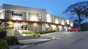 Un hotel llamado Bodega con diseño moderno, que presenta una escalera que conduce a la entrada, un área de estacionamiento y un coche rojo aparcado fuera.