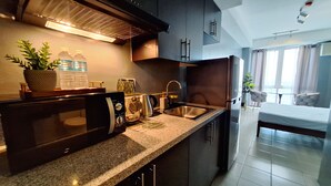 A modern kitchen with granite countertops, stainless steel appliances, and a built-in oven. - ELUDE Designer Suite Pasig (Prime location) (pasig city)