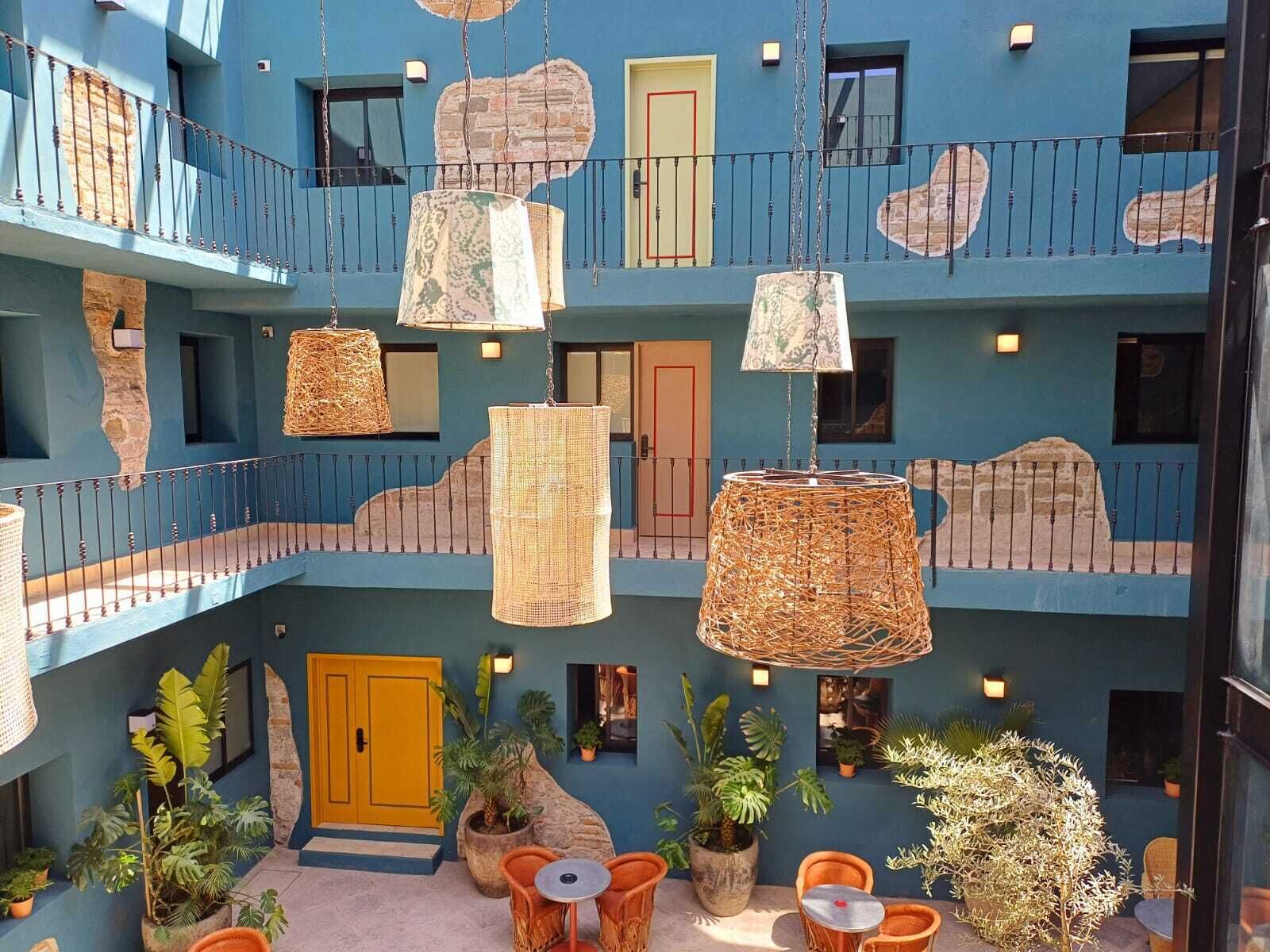 A multi-level atrium with hanging wicker lamps, potted plants, and outdoor seating.