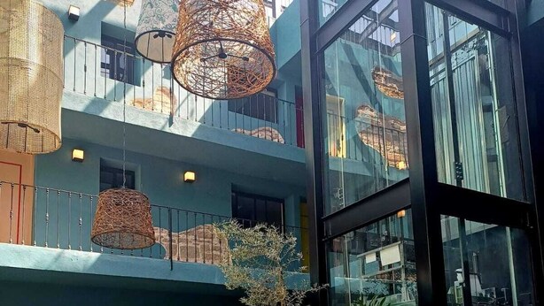 An outdoor seating area with wicker hanging lamps, potted plants, and wicker furniture. - Casa Nduxi (Puebla)