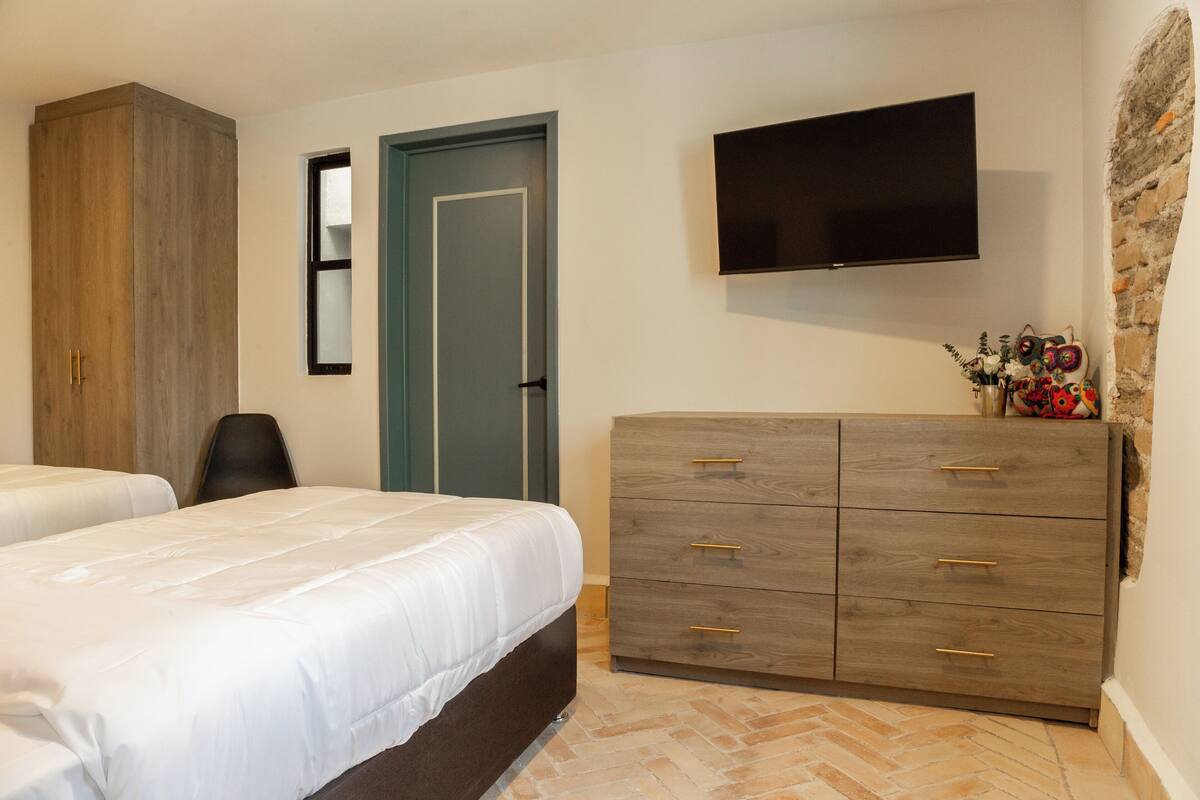 Un dormitorio con dos camas, un armario, un televisor y un adorno en la pared.