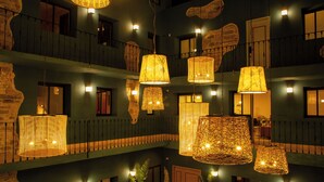A multi-level hotel interior with hanging wicker lamps and multiple balconies. - Casa Nduxi (Puebla)