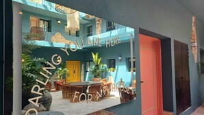 A courtyard with a dining area, a yellow door, and a sign that reads "DARLING YOU ARE HERE FOR A PURPOSE". - Casa Nduxi (Puebla)