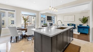 A modern kitchen with a large island, dark cabinetry, and pendant lighting. - Executive 5BR-4BATH Detached Retreat Brampton/Miss Border  (Brampton)