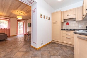 Une cuisine moderne avec des meubles en bois, un coin repas comprenant une table et des chaises, et une fenêtre visible avec des rideaux.