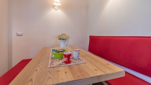 A wooden table with a red bench, a white vase with flowers, and two mugs on a placemat. - Villa Edelweiss Botton d'oro (Alleghe)