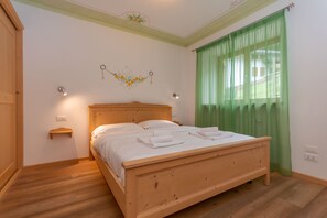 Une chambre à coucher avec un lit en bois, une table de chevet, une lampe fixée au mur et un rideau vert.